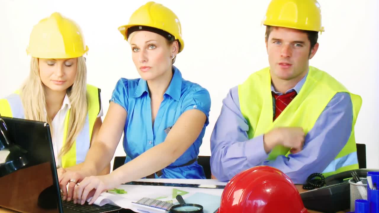 arquitectos usando una computadora portátil y sonriendo a la cámara en la oficina