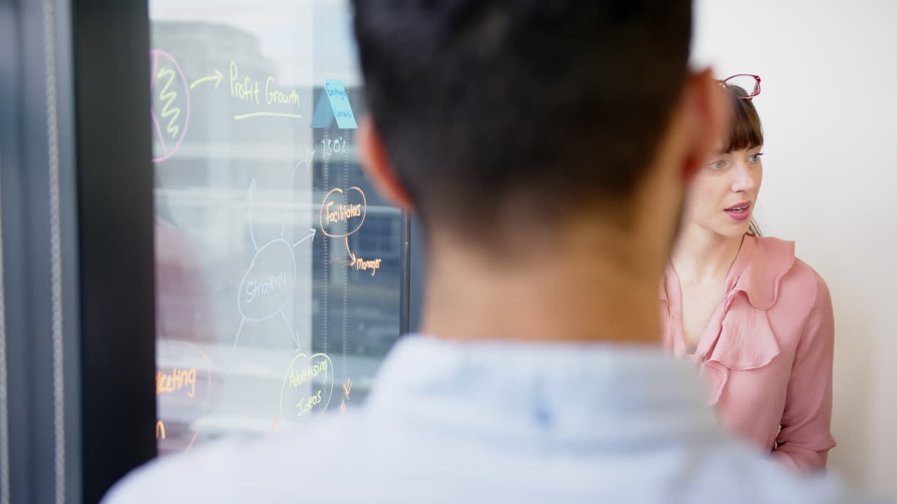 Writing on glass board, man brainstorming ideas in modern office setting