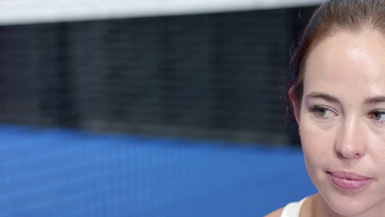 Young woman enjoying padel tennis game, smiling with focus on indoor court action, copy space