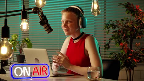 woman podcasting live from her home studio with "on air" sign