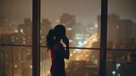 woman silhouette phone conversation in panoramic night luxury flat back view