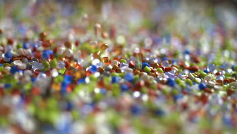 gránulos de plástico de colores cayendo sobre el espejo en cámara lenta