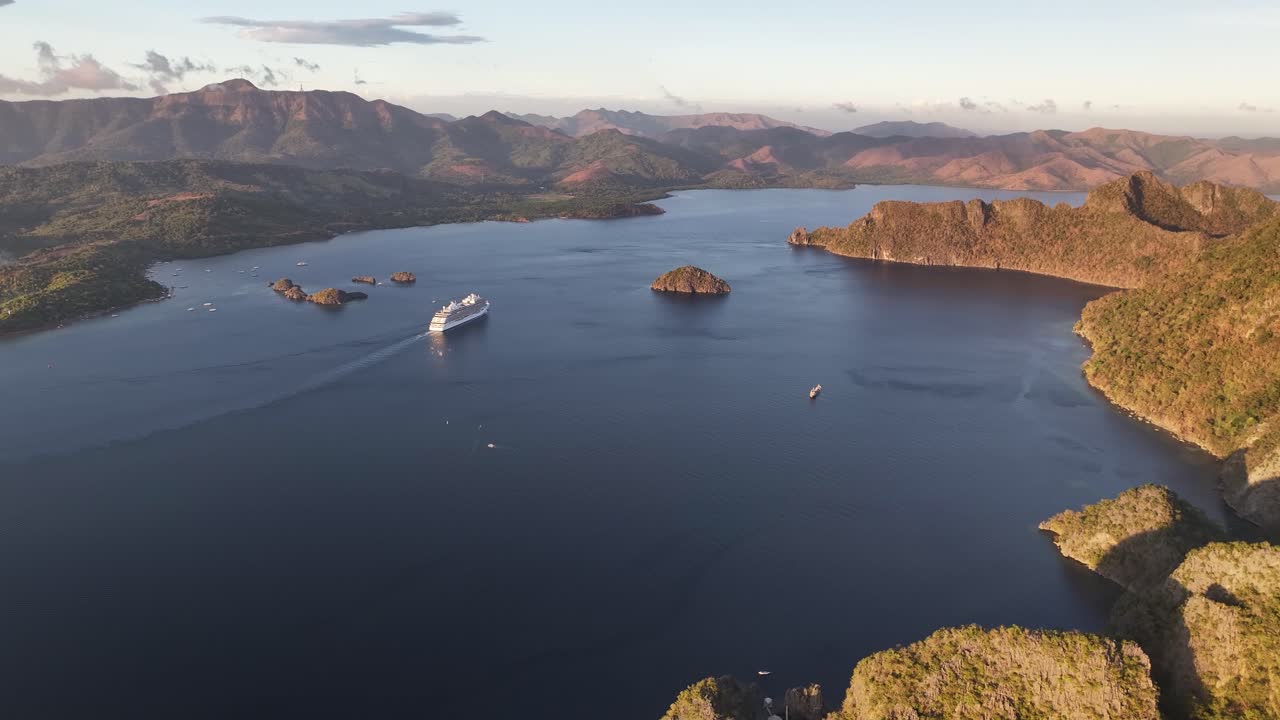 Cruise Ship Sailing Across Lake Surrounded By Mountainous Terrain At Dusk In Coron, Palawan. wide aerial shot
