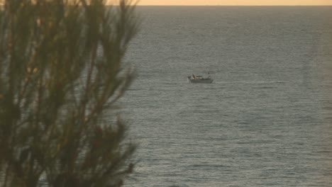 view from shore as a fisherman catches fish on his boat in the morning