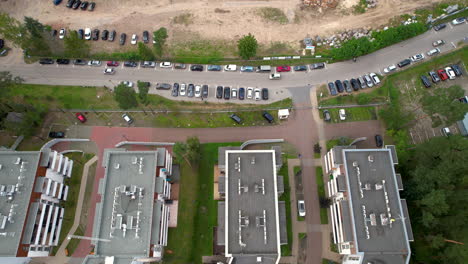 Toma-Aérea-Inclinada-Hacia-Arriba-De-Una-Zona-Residencial-Con-Coches-Conduciendo-Por-La-Carretera-En-La-Ciudad-De-Stegna,-Polonia