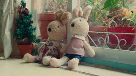 two toy rabbits sitting on a windowsill