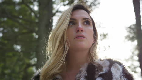 low angle close up shot of a stylish young woman posing in a winter forest, slow parallax shot