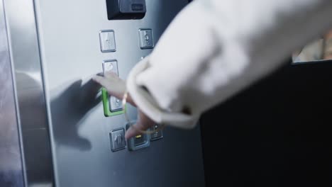 Midsection-of-biracial-businesswoman-using-elevator-in-office,-slow-motion