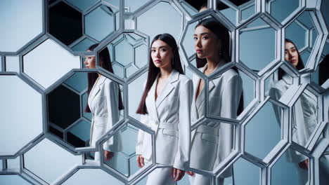 woman in white suit reflected in a hexagonal mirror installation
