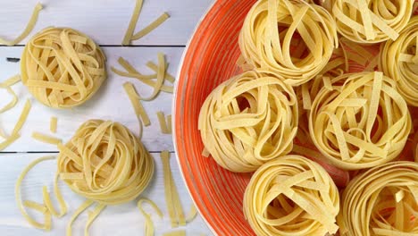 uncooked raw italian tagliatelle pasta rotating slowly on turntable in dish.