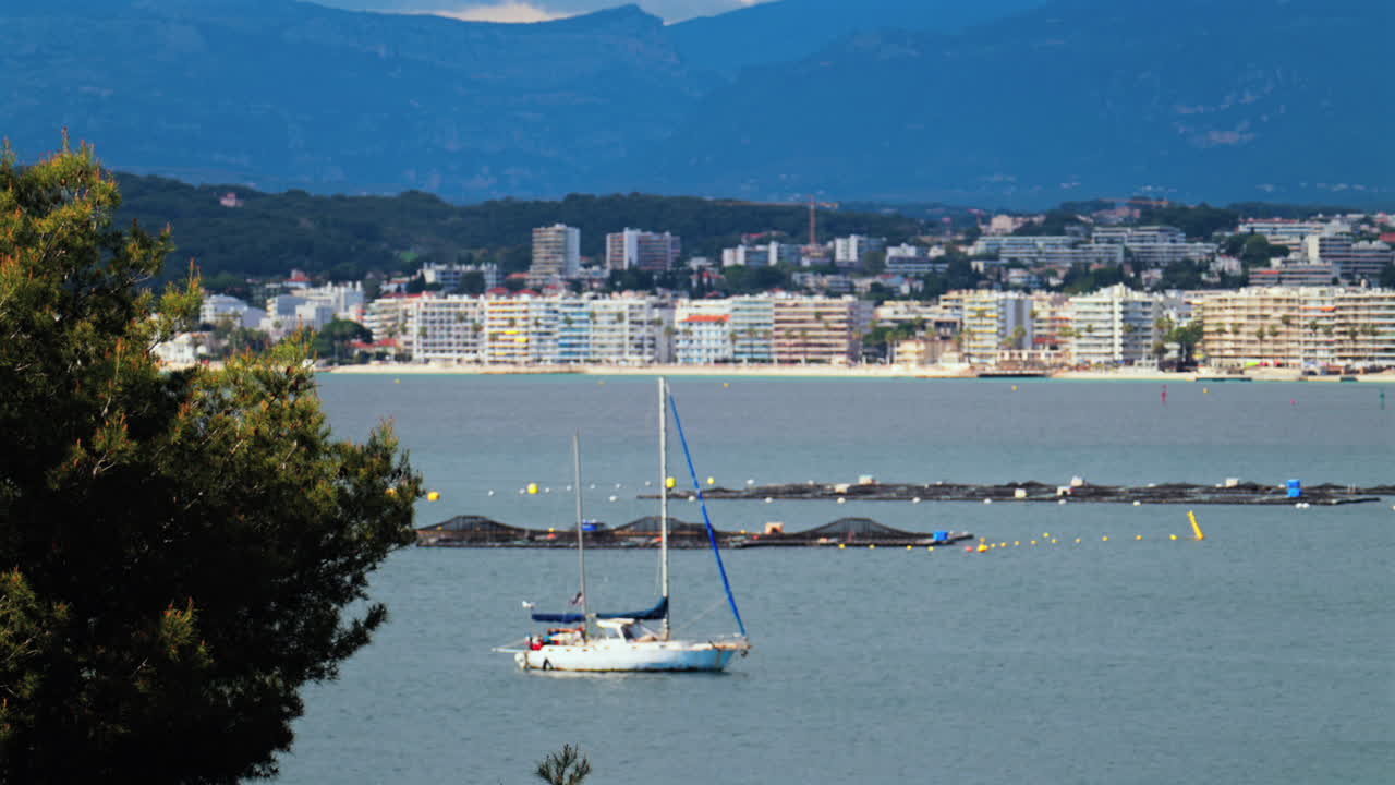 White boat docked on the sea with the buildings and the mountains on the background
