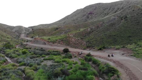 Vista-Aérea-De-Motos-Conduciendo-A-Lo-Largo-De-Carreteras-Remotas-A-Través-De-Valles-Montañosos-En-Khuzdar