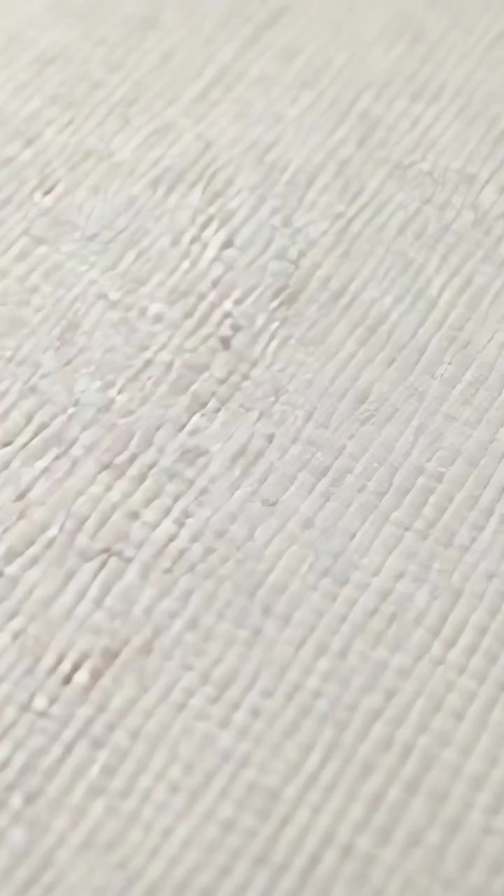 Video verticale: operatore che sposta la camera per riprendere un muro texturizzato in studio, catturando le scanalature
