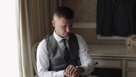 Man-in-suit-put-on-wrist-watch.-Groom-dresses.-Young-male-businessman-is-waiting-for-a-meeting