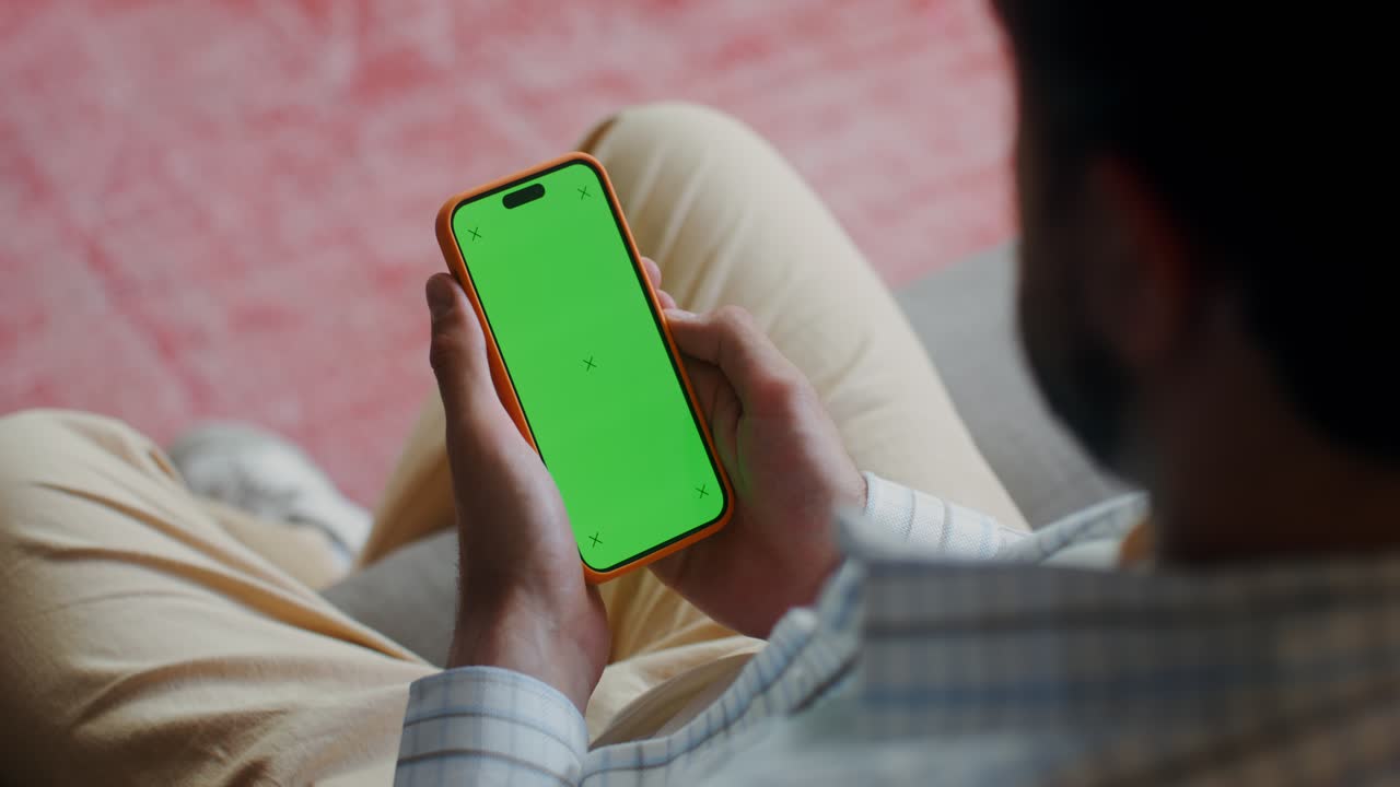 Person holding a smartphone with a green screen
