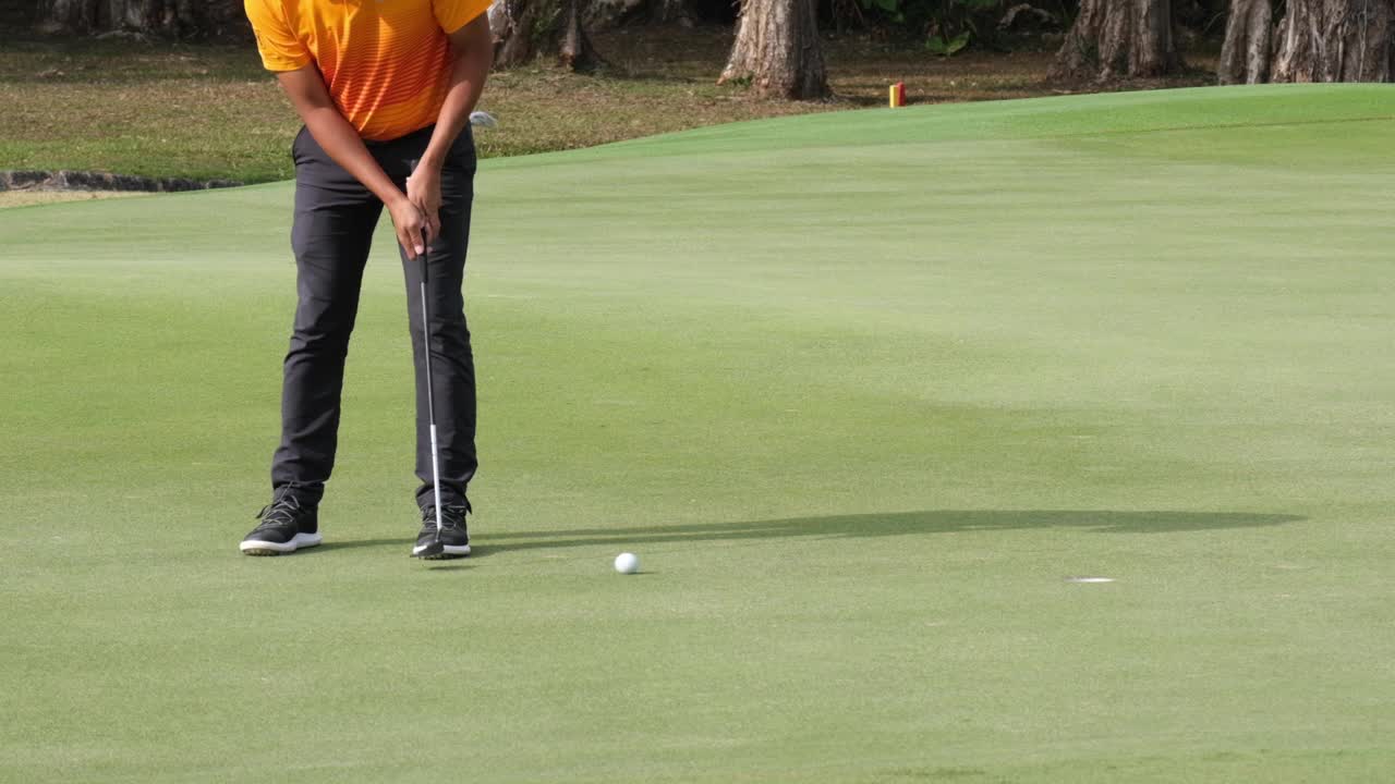 오픈 토너먼트 대회에서 언덕에 있는 그린 골프 코스에 있는 홀에 골프 공을 넣는 슬로우 모션 프로 골퍼