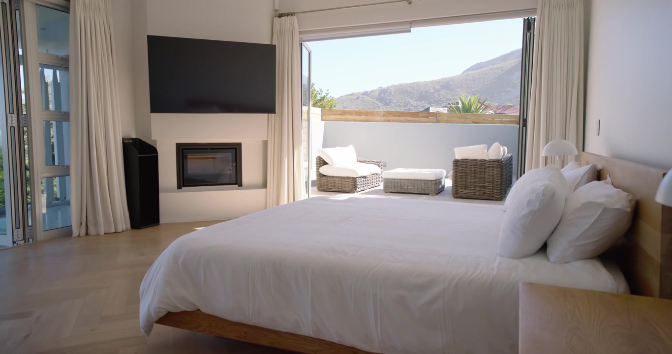 Camera is starting slow pass across master bedroom, revealing bed and balcony to show mountain