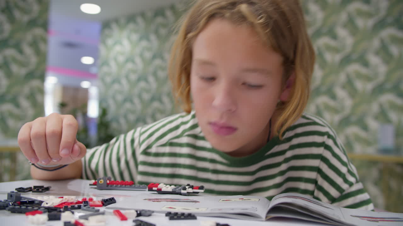 adolescente ensamblando bloques de plástico constructor en la cafetería