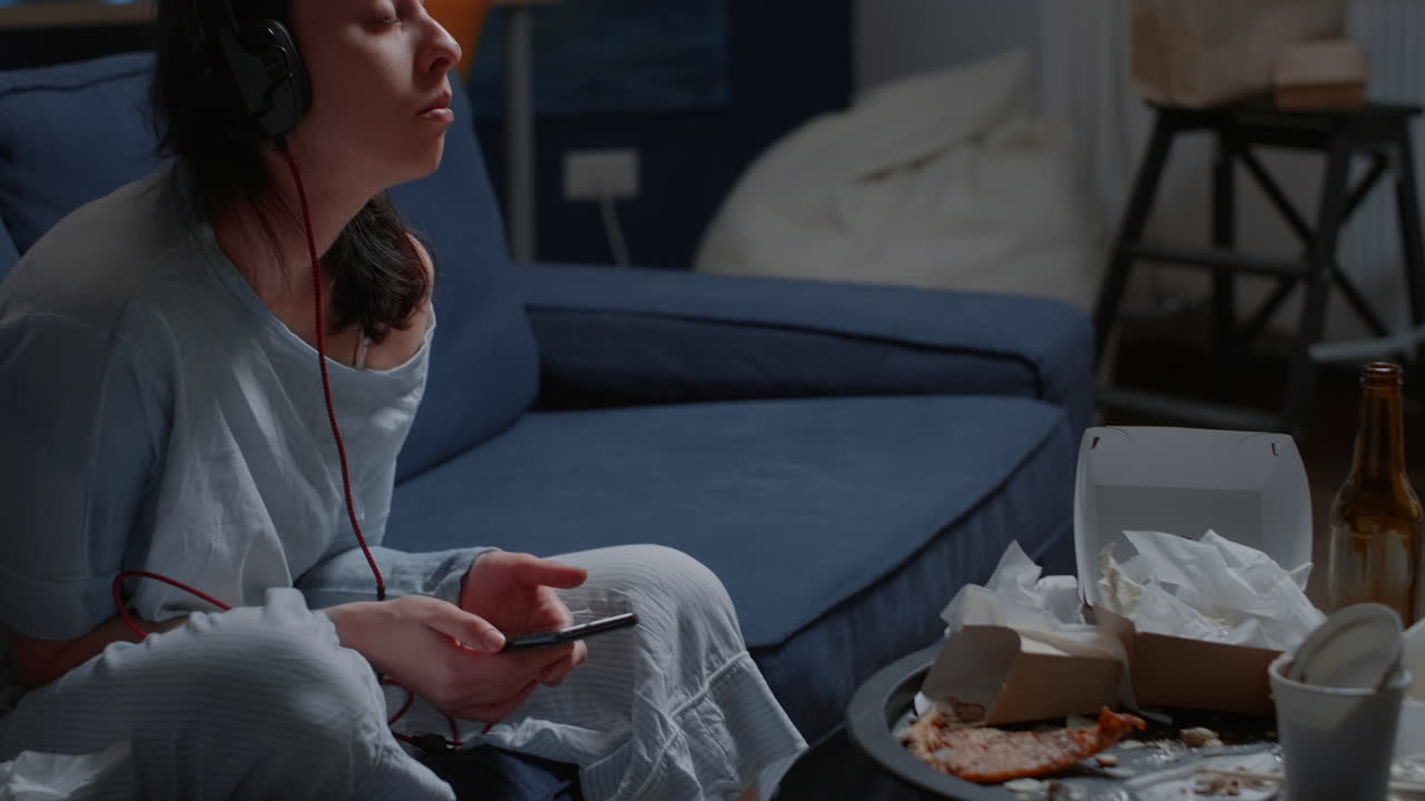 Thoughtful anxious woman listening sad music using smartphone