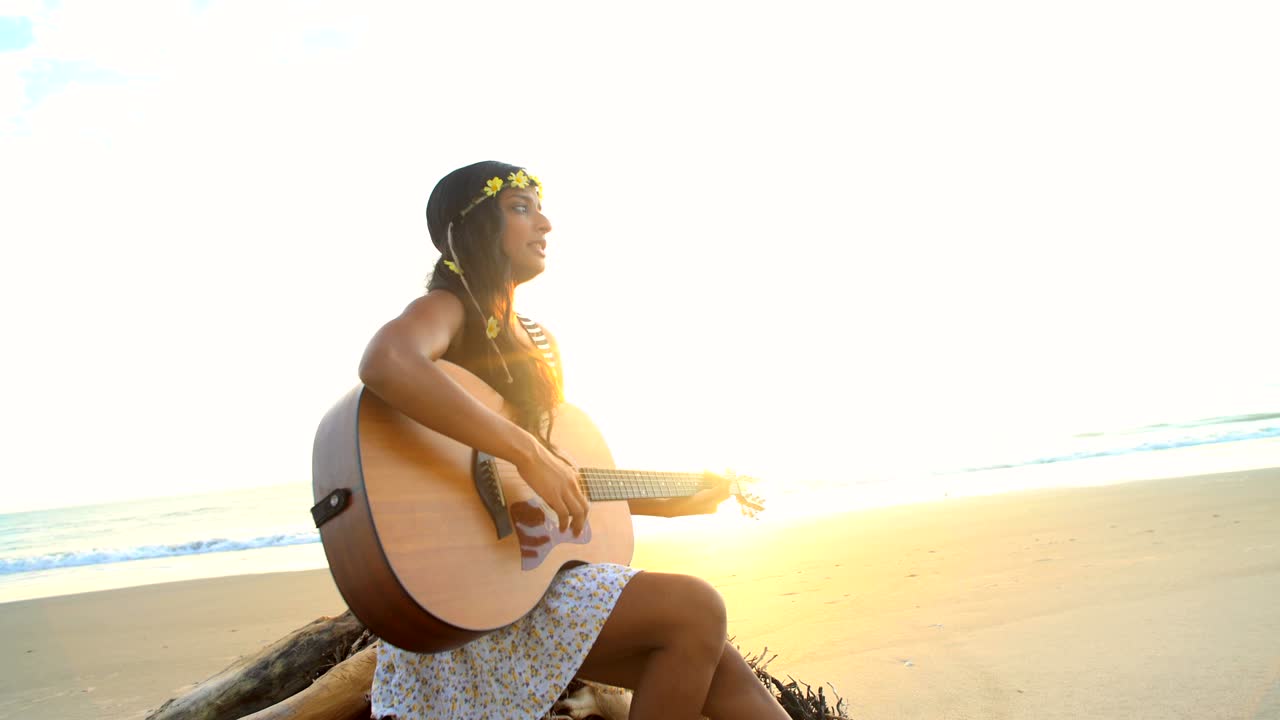 una chica india estadounidense con un vestido boho tocando la guitarra.