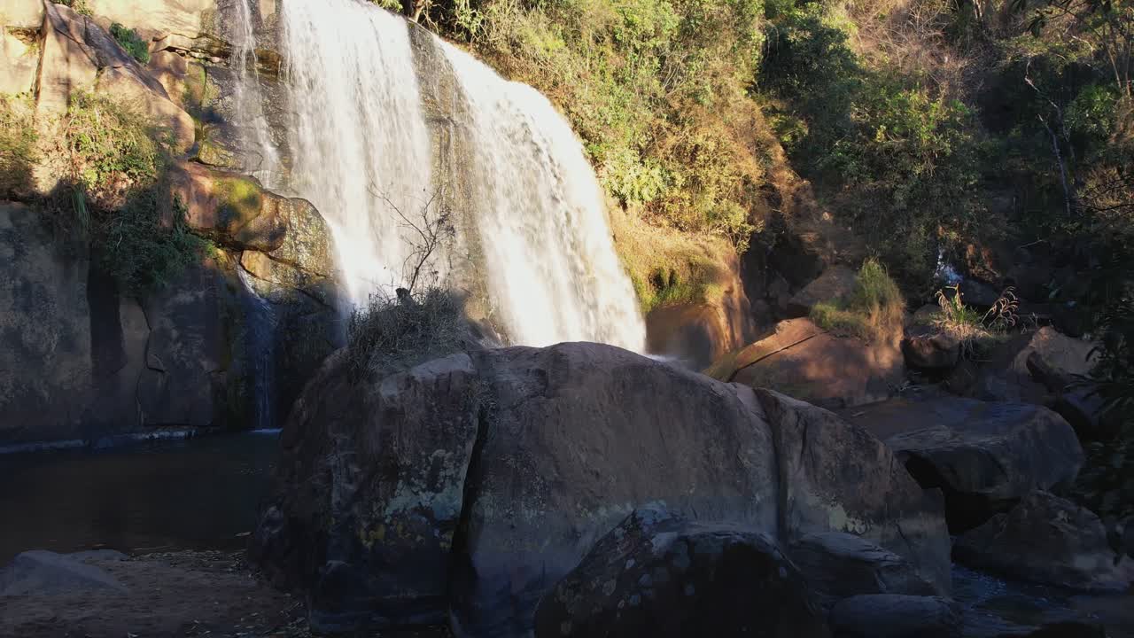 cámara alejándose para resaltar el área rocosa que rodea la cascada y su piscina de inmersión
