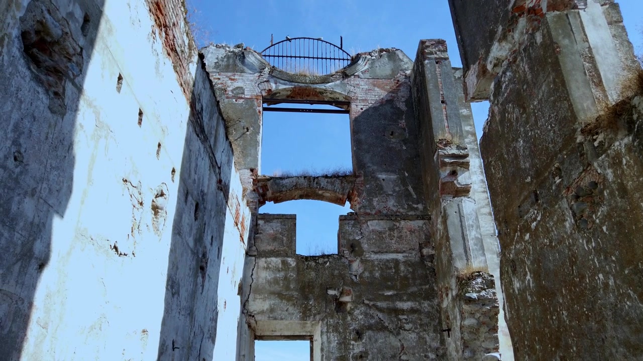 Inquadratura dal basso dell'architettura in pietra fatiscente e delle finestre vuote delle rovine storiche dell'Hacienda Coahuixtla sotto un cielo azzurro e limpido