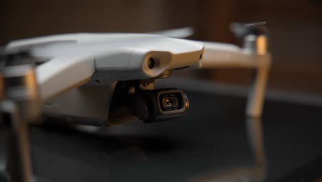 video cinematográfico de primer plano de un dron iluminado con una luz suave desde arriba y luces naranjas en el fondo, filmado en 4k con movimiento de cámara
