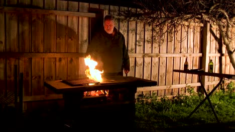 male cooking on a bbq and the oil burns startling the cook