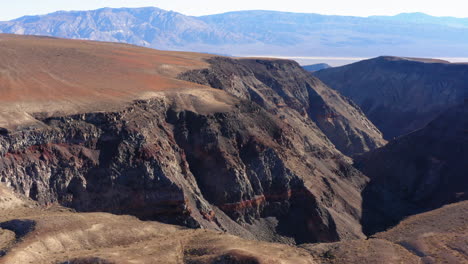 Aerial-close-up-view-of-a-colorful-canyon-called-Star-Wars-Canyon-on-a-sunny-day-with-a-mountain-range-in-the-background