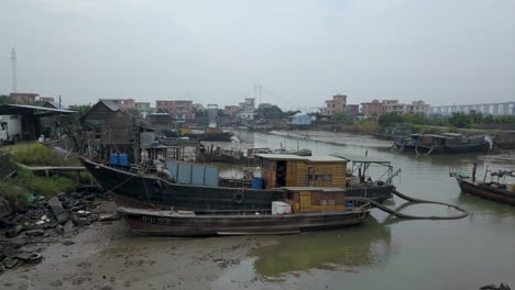 Aerial-shot-of-a-boat-approaching-a-berth-on-a-polluted-river-in-Asia