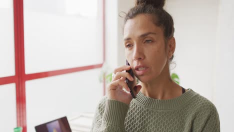 Video-of-happy-biracial-female-designer-using-smartphone-in-studio