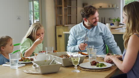 Vater-Serviert-Essen,-Während-Die-Familie-Zu-Hause-Am-Tisch-Sitzt-Und-Gemeinsam-Das-Essen-Genießt