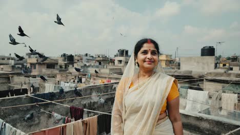 indian woman wearing a traditional white sari stands on a rooftop, surrounded by clothes hanging on a line and pigeons flying in the sunny sky, embodying cultural heritage and everyday life