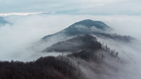 misty mountain peaks emerging above soft clouds, serene and majestic