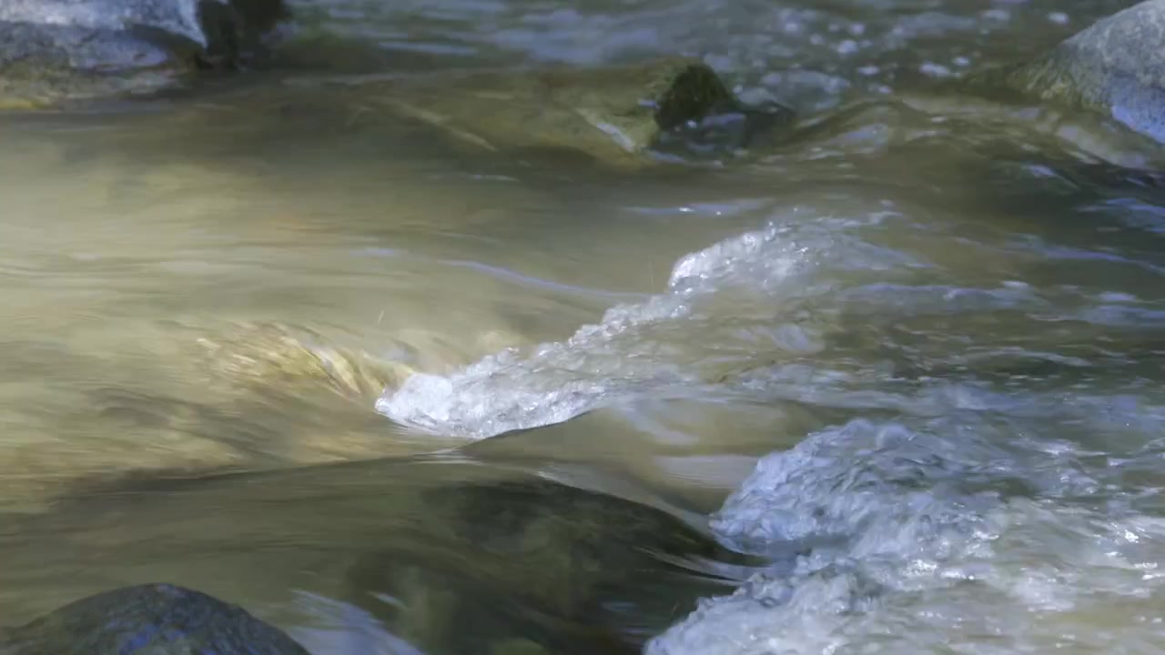 Acqua dolce limpida di un ruscello forestale poco profondo, che increspa le rocce del fiume mentre gorgoglia e schizza. Clip E
