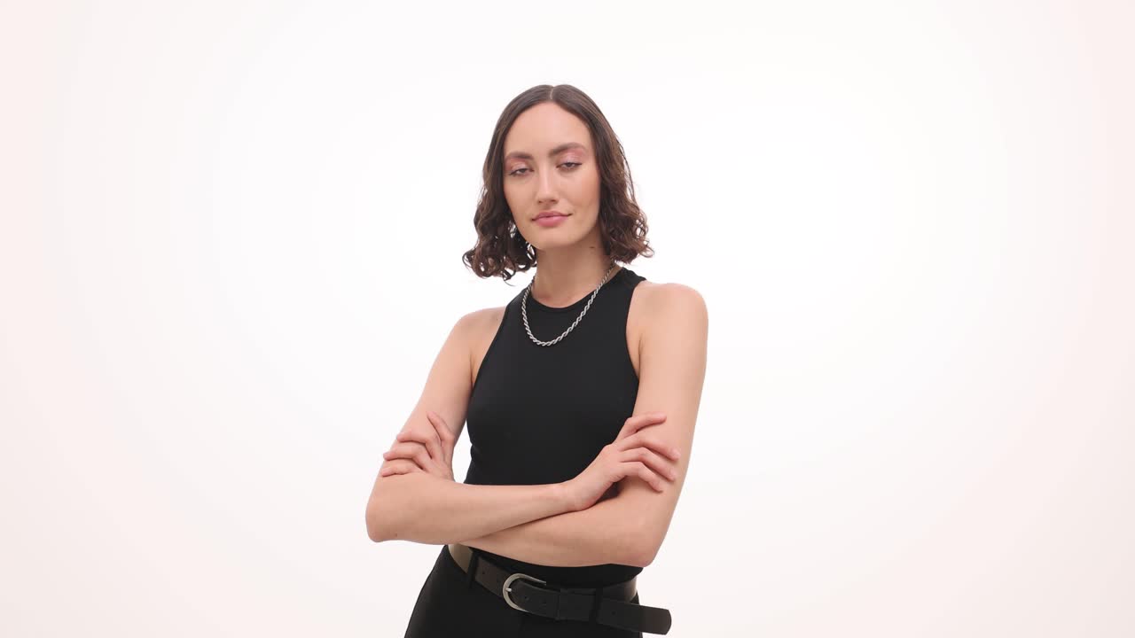 Confident woman in black posing with arms crossed against white background