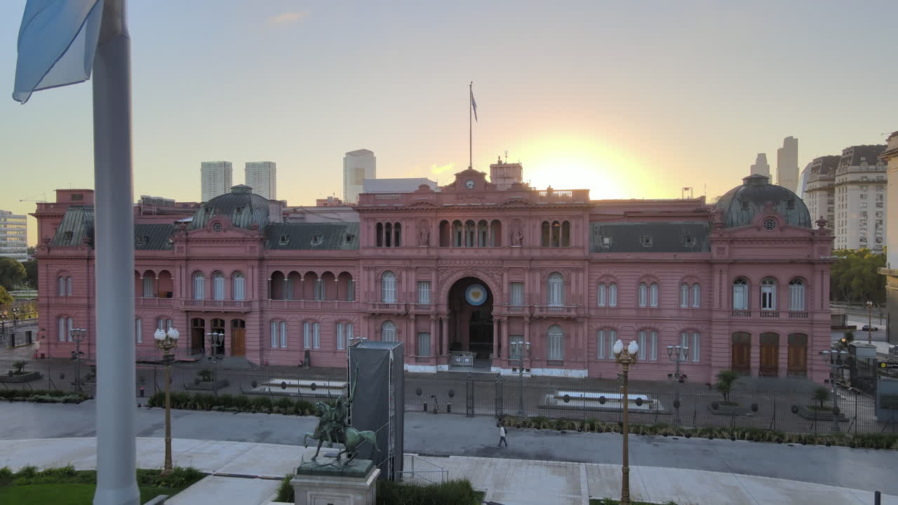 Aerial Drone Scene flying back of Casa Rosada, Buenos Aires, Argentina, the presidential pink house. Warm dawn morning sun backlight of Historic building and flag. Flare, reflections.