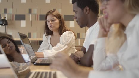 equipo de inicio sentado a la mesa con computadoras portátiles