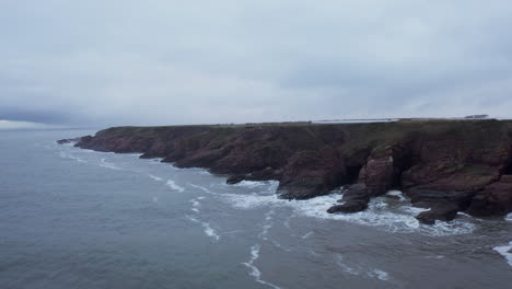 Tiro-De-Dron-De-Los-Acantilados-En-El-Norte-De-Escocia-En-Un-Día-Gris-Mientras-Las-Olas-Chocan-Contra-Ellos