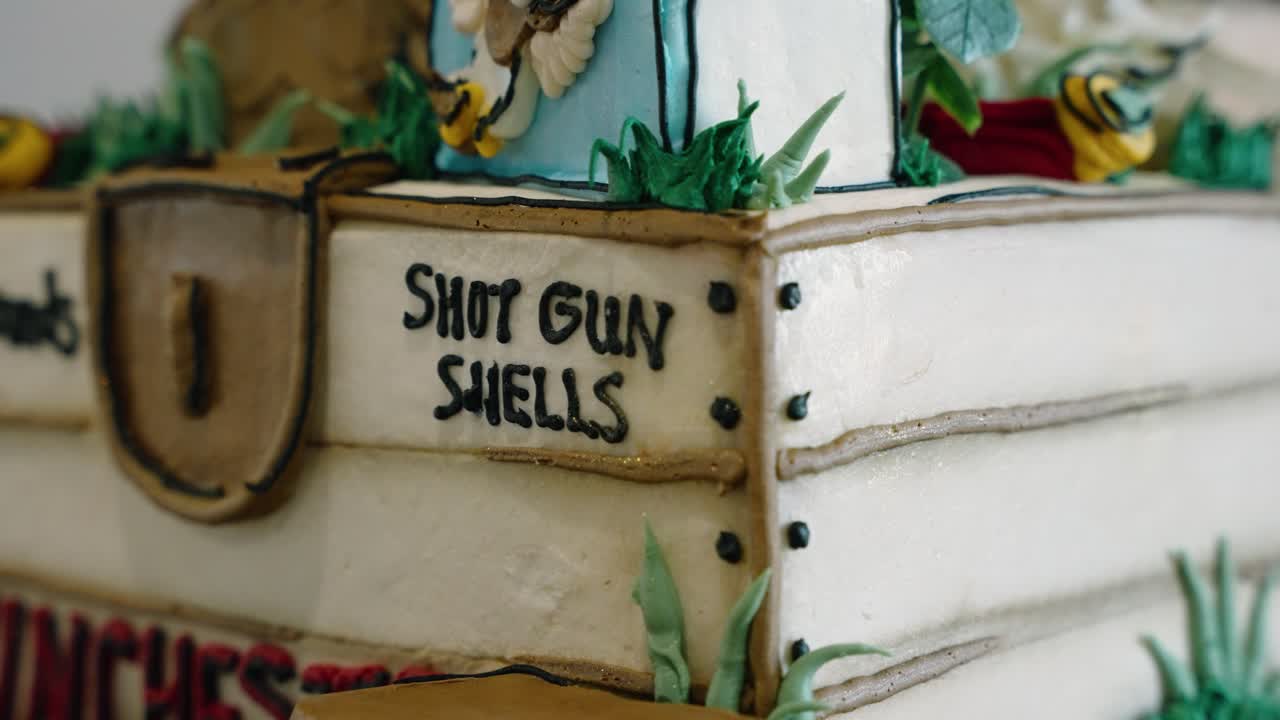 Detailed close-up of a unique duck-themed groom’s wedding cake with shotgun shell design elements. The cake mimics a wooden box with intricate details, perfect for an outdoor or rustic wedding theme.