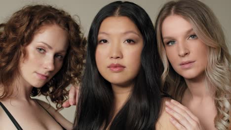 close up of three women standing close and looking towards the camera.