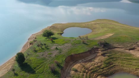 small flooded pond in rama lake bosnia and herzegovina on a peninsula with eroded shore, aerial flyover shot