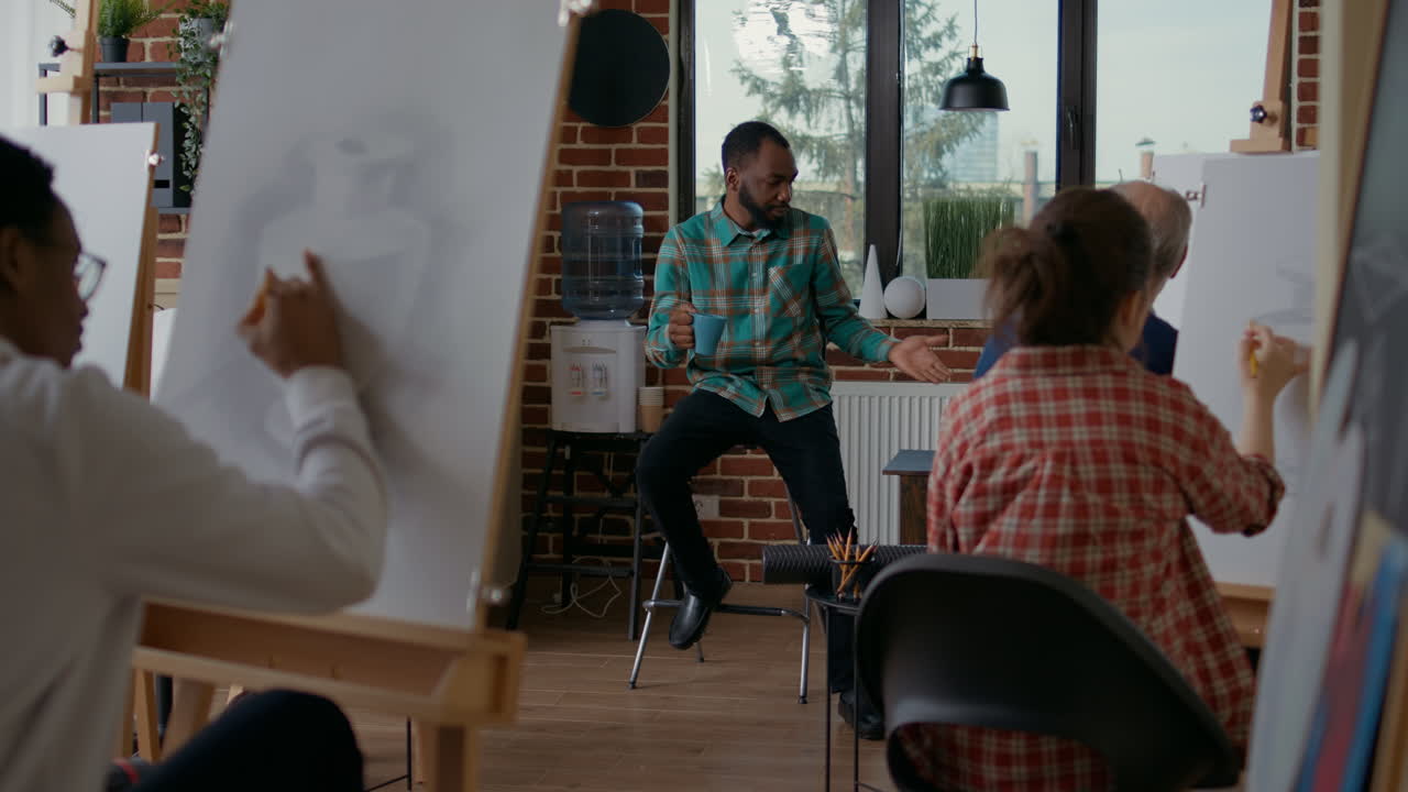 Young man teaching creative people to draw on canvas