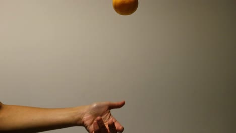 a hand throws and catches an orange