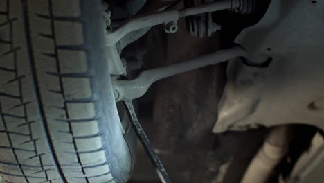 mechanic with flashlight repairs a car wheel, close up