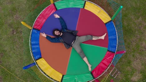 man lying on a colorful trampoline in the countryside of mantiqueira, minas gerais