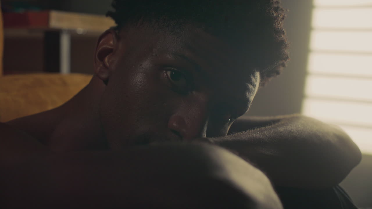 Portrait of Young African American Man Resting Head on Arms in Bedroom