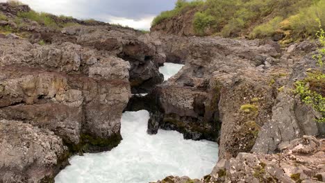 The fantastic waterfall Barnafossar with the water flowing around the big rock formation that's surrounding it