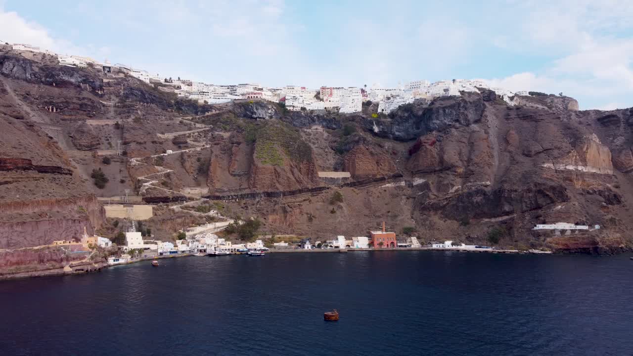 vista de avión no tripulado del puerto de santorini: atraque de cruceros, terminal de transbordadores y base de góndolas con camino a pie a la cima