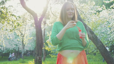 merry pregnant woman among blooming trees